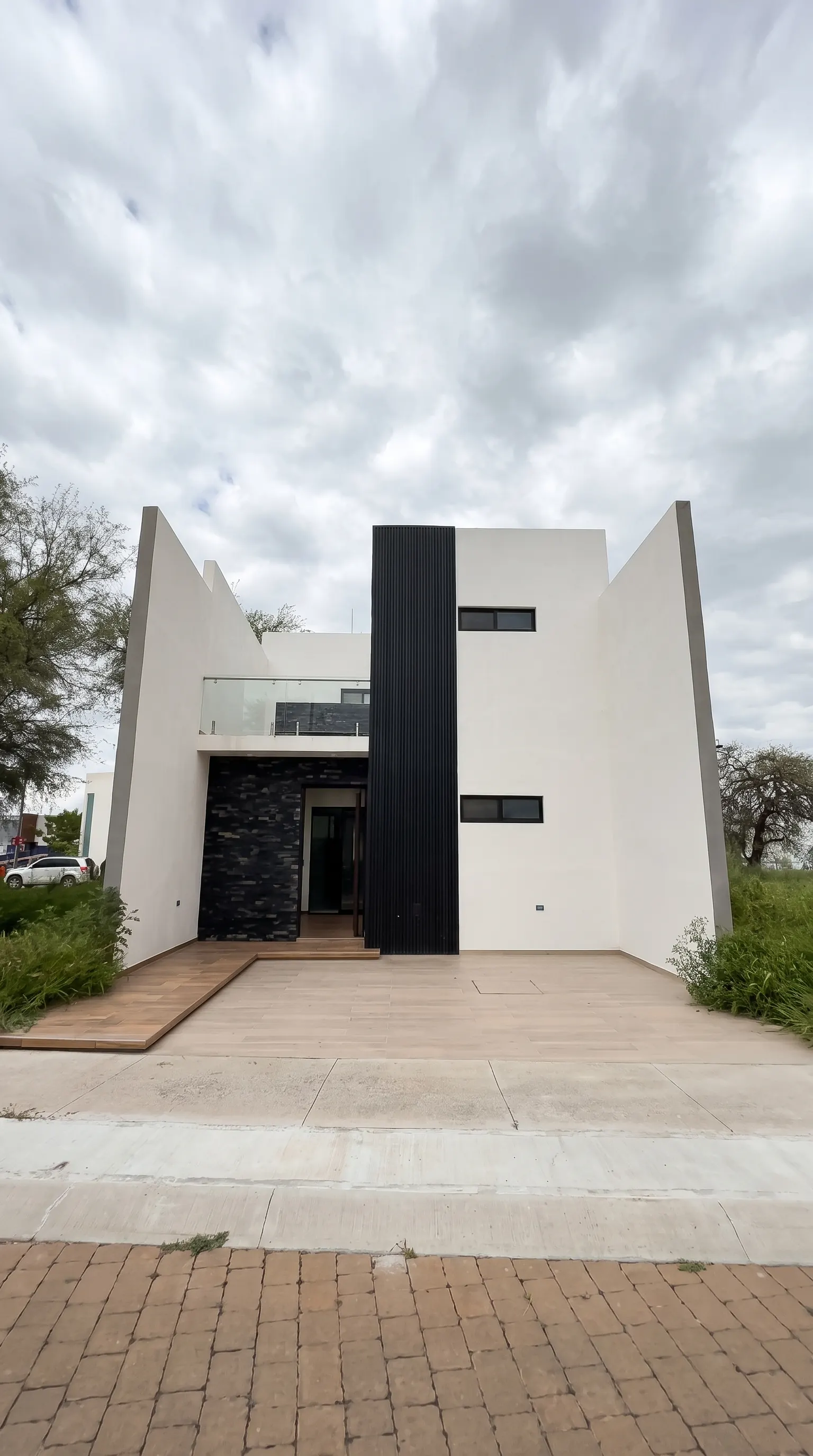 Fachada principal moderna con columna negra y cochera para dos autos, Santa Bárbara Residencial