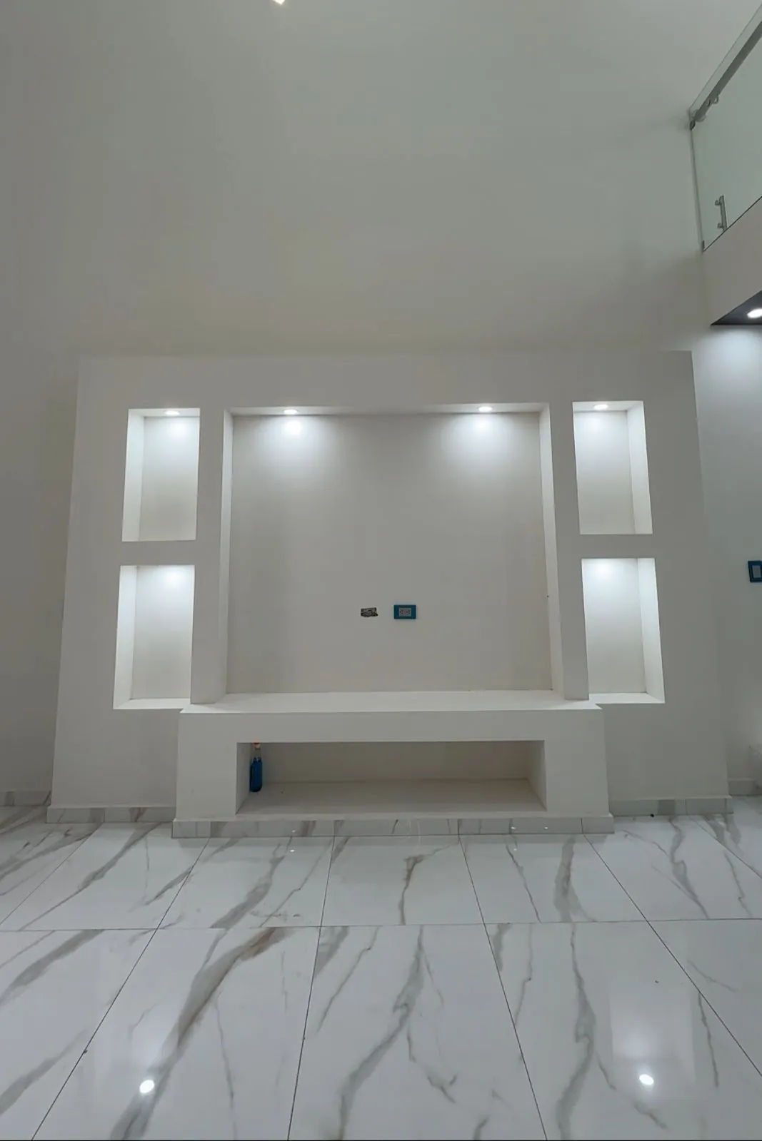 Sala con muro de TV y nichos iluminados, piso de porcelanato tipo mármol, Santa Bárbara Residencial